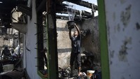 Warga menyiramkan air di bangunan tempat tinggalnya yang telah hangus terbakar di kawasan Pinangsia, Tamansari, Jakarta, Minggu (19/4/2020).