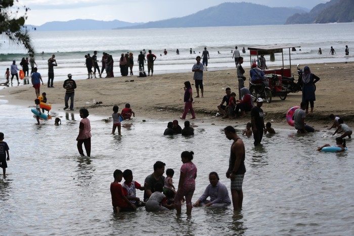 Wisatawan yang tidak mengenakan masker memadati pantai wisata Lhoknga di Aceh Besar, Aceh, Minggu (19/4/2020). Warga masih mengabaikan imbauan pemerintah untuk mengenakan masker, menjaga jarak, serta tidak berkumpul di tempat publik sebagai upaya memutus rantai penyebaran COVID-19. ANTARA FOTO/Irwansyah Putra/aww.