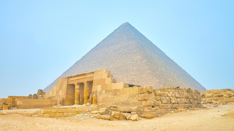 makam ratu mesir The preserved entrance with columns of the Mastaba (Tomb) of Queen Meresankh III with the Pyramid of Khufu on the background, Giza complex, Egypt