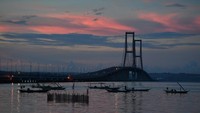 Nelayan menambatkan perahunya di sisi timur Jembatan Suramadu di Surabaya, Jawa Timur, saat matahari tenggelam. Jumlah pengunjung menurun drastis seiring kebijakan stay at home karena pandemi Corona.