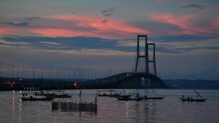 Sejumlah warga menikmati senja di pantai sisi timur Jembatan Suramadu di Surabaya, Jawa Timur, Jumat (17/4/2020). Akibat pandemi virus Corona (COVID-19), suasana di kawasan itu sepi pengunjung. ANTARA FOTO/Zabur Karuru/wsj.