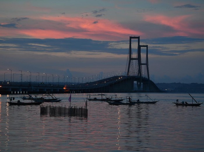 Sejumlah warga menikmati senja di pantai sisi timur Jembatan Suramadu di Surabaya, Jawa Timur, Jumat (17/4/2020). Akibat pandemi virus Corona (COVID-19), suasana di kawasan itu sepi pengunjung. ANTARA FOTO/Zabur Karuru/wsj.