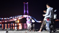 Hanya tampak segelintir pasangan muda-mudi yang mengunjungi pantai sisi timur Jembatan Suramadu di Surabaya, Jawa Timur, Sabtu (18/4/2020) malam untuk sekadar berfoto.