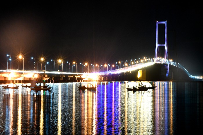 Sejumlah warga menikmati senja di pantai sisi timur Jembatan Suramadu di Surabaya, Jawa Timur, Jumat (17/4/2020). Akibat pandemi virus Corona (COVID-19), suasana di kawasan itu sepi pengunjung. ANTARA FOTO/Zabur Karuru/wsj.