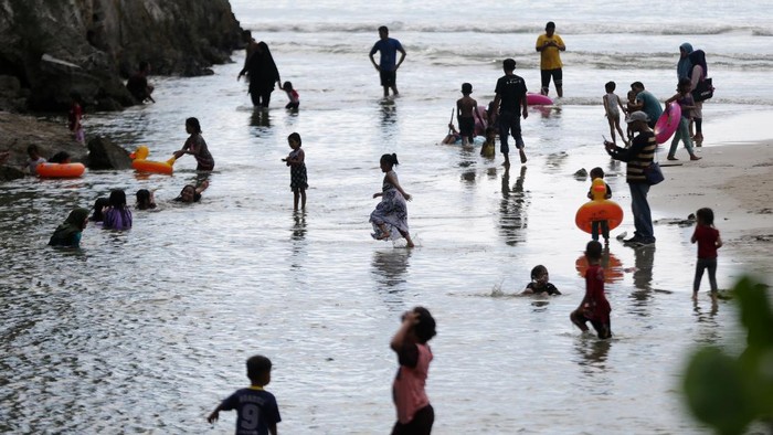Wisatawan yang tidak mengenakan masker memadati pantai wisata Lhoknga di Aceh Besar, Aceh, Minggu (19/4/2020). Warga masih mengabaikan imbauan pemerintah untuk mengenakan masker, menjaga jarak, serta tidak berkumpul di tempat publik sebagai upaya memutus rantai penyebaran COVID-19. ANTARA FOTO/Irwansyah Putra/aww.