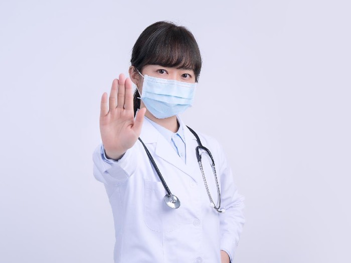 ilustrasi dokter memakai masker Young female doctor woman wearing mask, making stop sign gesture, saying No isolated on white background, refusing virus disease, close up, blank.