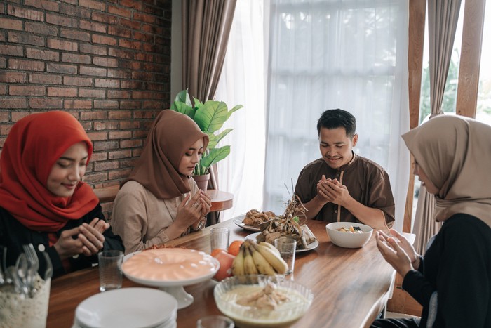 asian muslim people praying before having their food in dining room together for break fasting