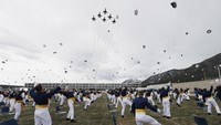 Mereka melemparkan topi ke udara saat Air Force Thunderbirds melintas sebagai pertanda telah selesai mengikuti sekolah di akademi tersebut.