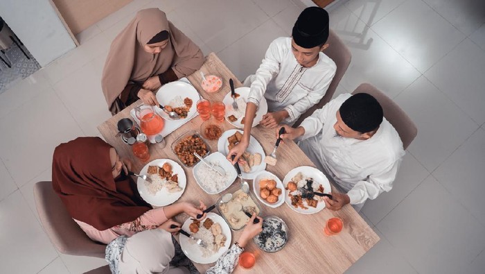 asian muslim people praying before having their food in dining room together for break fasting