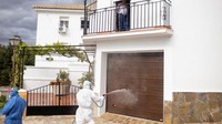  Seorang warga Zahara tengah menyaksikan dari balkon ketika para sukarelawan membasmi menyemprotkan disinfektan di jalan-jalan kota.