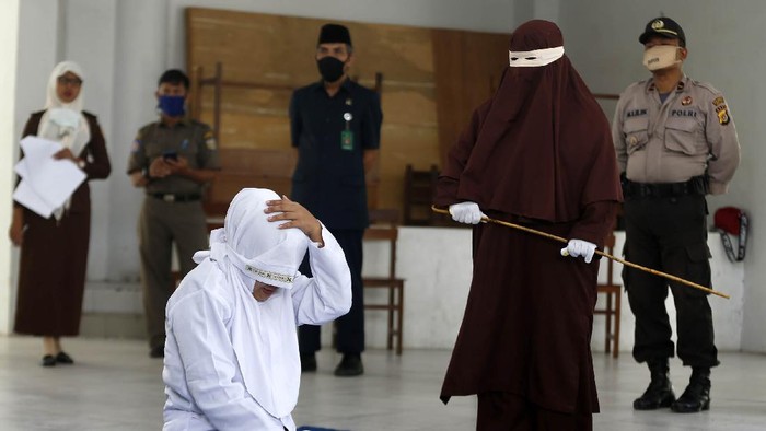 Terpidana (duduk) pelanggar hukum syariat Islam dieksekusi cambuk di Banda Aceh, Aceh, Selasa (21/4/2020). Enam terpidana pelanggar peraturan daerah (qanun) nomor 6/2020 tentang hukum jinayat tetap di eksekusi cambuk ditengah darurat pandemi COVID-19 dengan menjaga jarak sosial (phsycal distancing) dan prosedur kesehatan. ANTARA FOTO/Irwansyah Putra/hp.