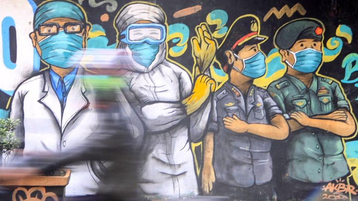 Pengendara melintas di depan mural tentang pandemi COVID-19 di Kawasan Bangil, Pasuruan, Sidoarjo, Jawa Timur, Senin (20/4/2020). Mural tersebut dibuat bertujuan untuk mensosialisasikan dan mengedukasi warga agar tetap waspada terhadap potensi penyebaran virus corona atau COVID-19. ANTARA FOTO/Umarul Faruq/wsj.