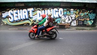 engendara melintas di depan mural tentang pandemi COVID-19 di Kawasan Bangil, Pasuruan, Sidoarjo, Jawa Timur, Senin (20/4/2020). ANTARA FOTO/Umarul Faruq