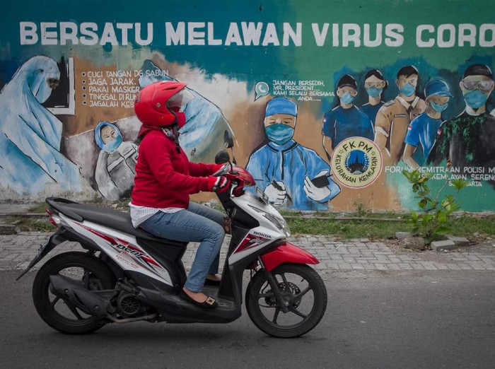 Pengendara melintas di depan mural tentang pandemi COVID-19 di Kawasan Bangil, Pasuruan, Sidoarjo, Jawa Timur, Senin (20/4/2020). Mural tersebut dibuat bertujuan untuk mensosialisasikan dan mengedukasi warga agar tetap waspada terhadap potensi penyebaran virus corona atau COVID-19. ANTARA FOTO/Umarul Faruq/wsj.