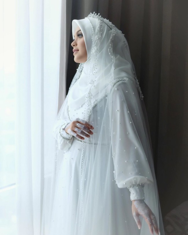 Melalui akun Instagramnya, sang desainer Renzi Lazuardi baru menguak rahasia pembuatan gaun pengantin tersebut setelah Vebby Palwinta resmi menikah. Vebby nanya “Kak Renzi ada dress putih ready?”. Aku bilang adaaa, tenang ajaa *biar Vebby ngga panik*.. Padahaaal aku bikinin baru dress sama veil-nya dalam waktu 5 hari, bukan pake yang udah ada.. Dan ini baru aku bongkar rahasia ini di sini.. *Maaf ya Veb udah bo’ongin kamu* 🙈 Dress-nya emg ngga heboh payetnya sampe bleneg, karena kayanya ngga pas juga sama tempatnya.. Jadi aku bikinin yang simpel, manis, syahdu aja buat Vebby.. Semoga Vebby berkenan yaa.., begitu sang desainer menulis di Instagram @renzilazuardi. Foto: Instagram @renzilazuardi
