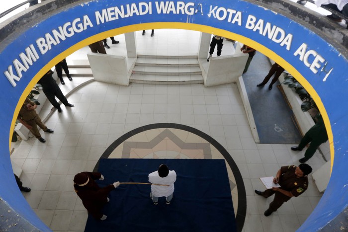 Terpidana (duduk) pelanggar hukum syariat Islam dieksekusi cambuk di Banda Aceh, Aceh, Selasa (21/4/2020). Enam terpidana pelanggar peraturan daerah (qanun) nomor 6/2020 tentang hukum jinayat tetap di eksekusi cambuk ditengah darurat pandemi COVID-19 dengan menjaga jarak sosial (phsycal distancing) dan prosedur kesehatan. ANTARA FOTO/Irwansyah Putra/hp.