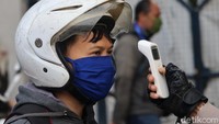 Tak hanya pengendara roda empat, petugas juga turut memeriksa dan mengukur suhu tubuh para pengendara roda dua yang masih beraktivitas di luar rumah.
