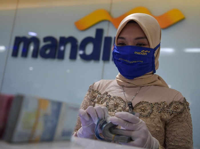 Karyawan Bank Mandiri mengenakan pakaian adat kebaya menghitung uang saat melayani nasabah di salah satu kantor cabang di Jatinegara, Jakarta, Selasa (21/4/2020). Penggunaan pakaian adat ini dalam rangka memperingati Hari Kartini yang dilakukan karyawan Bank Mandiri di tengah kebijakan penerapan Pembatasan Sosial Berskala Besar (PSBB) untuk memutus mata rantai penyebaran pandemi COVID-19. ANTARA FOTO/Nova Wahyudi/foc.