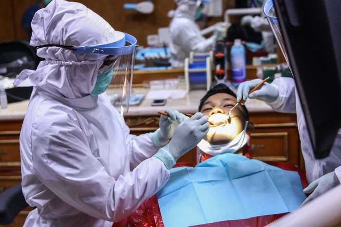 Ditengah pandemi virus Corona, dokter gigi di Jakarta, memakai APD saat tengah memeriksa pasien. Hal itu dilakukan guna cegah penyebaran COVID-19.
