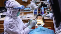 Seorang pasien tengah diperiksa oleh dokter gigi yang menggunakan Alat Pelindung Diri (APD) di salah satu klinik gigi di Jakarta.