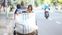 Dua orang anak tampak duduk di dalam gerobak saat melintasi salah satu jalan yang berada di kawasan Jakarta.