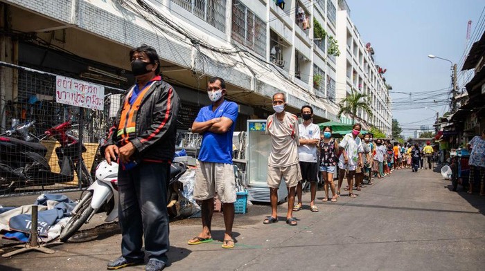 Warga pemukiman padat penduduk Pathumwan mengantri pembagian makanan, air mineral dan masker di Bangkok, Thailand (22/4/2020). Pembagian paket makanan berlangsung tertib, tetap menjaga jarak, tidak berdesak-desakan. Patut ditiru.