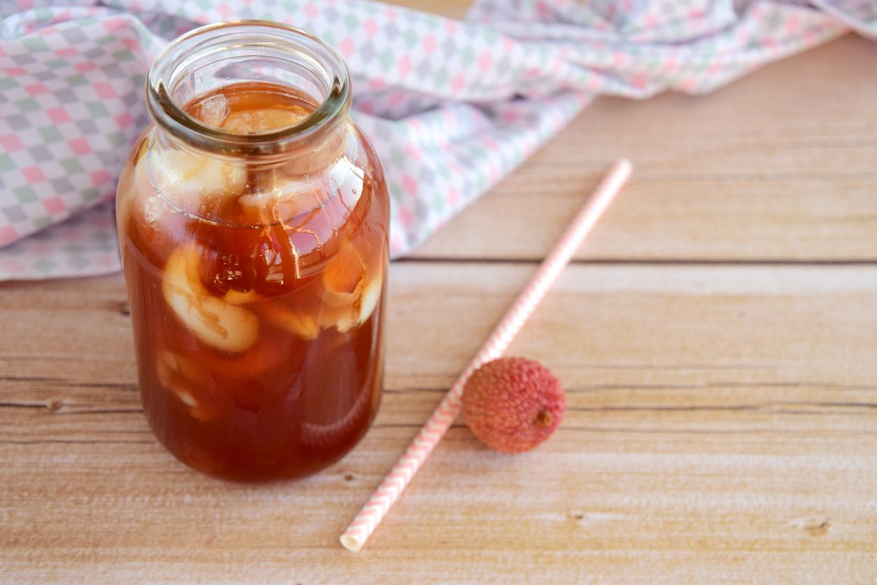 Refreshing with a glass of iced tea add lime, lychee juice and soda on the wooden table, blur background, selective focus.