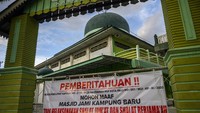 Sebuah spanduk pemberitahuan tidak melaksanakan shalat berjamaan dibentangkan di pintu gerbang Masjid Jami, Kampung Baru, Palu, Sulawesi Tengah, Kamis (23/4/2020). Gubernur Sulawesi Tengah mengeluarkan instruksi yang berisi imbauan untuk tidak melaksanakan shalat berjamaah di masjid selama Ramadhan untuk menghindari penyebaran COVID-19 termasuk shalat tarawih. ANTARAFOTO/Basri Marzuki