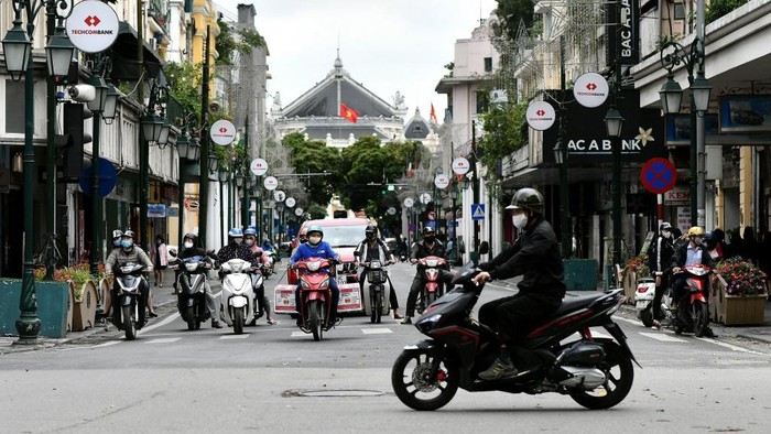 Motorists are seen at a traffic intersection in Hanoi on April 23, 2020, as Vietnam eased its nationwide social isolation effort to prevent the spread of the COVID-19 novel coronavirus. - Vietnam eased social distancing measures on April 23, with experts pointing to a decisive response involving mass quarantines and expansive contact tracing for the apparent success in containing the coronavirus. (Photo by Manan VATSYAYANA / AFP)