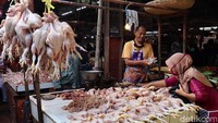 Pedagang daging ayam berbincang dengan pedagang lainnya sambil menunggu pembeli.