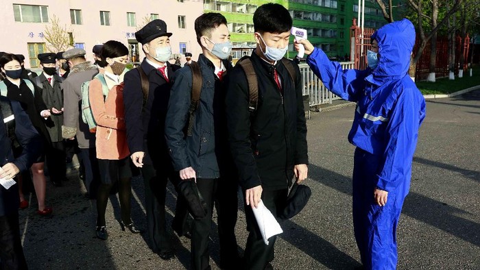 Students wearing a face mask have their temperature checked as a precaution against a new coronavirus as their university reopened following vacation, at Kim Chaek University of Technology in Pyongyang, Wednesday, April 22, 2020. (AP Photo/Jon Chol Jin)