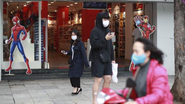 People walk out from a shop in Hanoi, Vietnam Thursday, April 23, 2020. The world inched toward a new phase in the coronavirus crisis on Thursday, as some countries like Vietnam and New Zealand with few new cases moved toward ending their shutdowns while others like Singapore and Japan were tightening measures to prevent a surge in infections. (AP Photo/Hau Dinh)