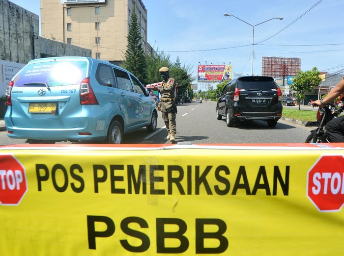 Petugas memeriksa penumpang di dalam kendaraan yang melintas di Posko Check Point Pembatasan Sosial Berskala Besar (PSBB) di Air Tawar, Padang, Sumatera Barat, Rabu (22/4/2020). PSBB diterapkan di Padang dan kabupaten/ kota lain di provinsi itu mulai Rabu (22/4/2020) hingga 5 Mei 2020 untuk menghentikan penyebaran COVID-19, diantaranya dengan membatasi aktivitas di luar rumah, wajib menggunakan masker serta pembatasan jumlah penumpang kendaraan roda empat dan roda dua.