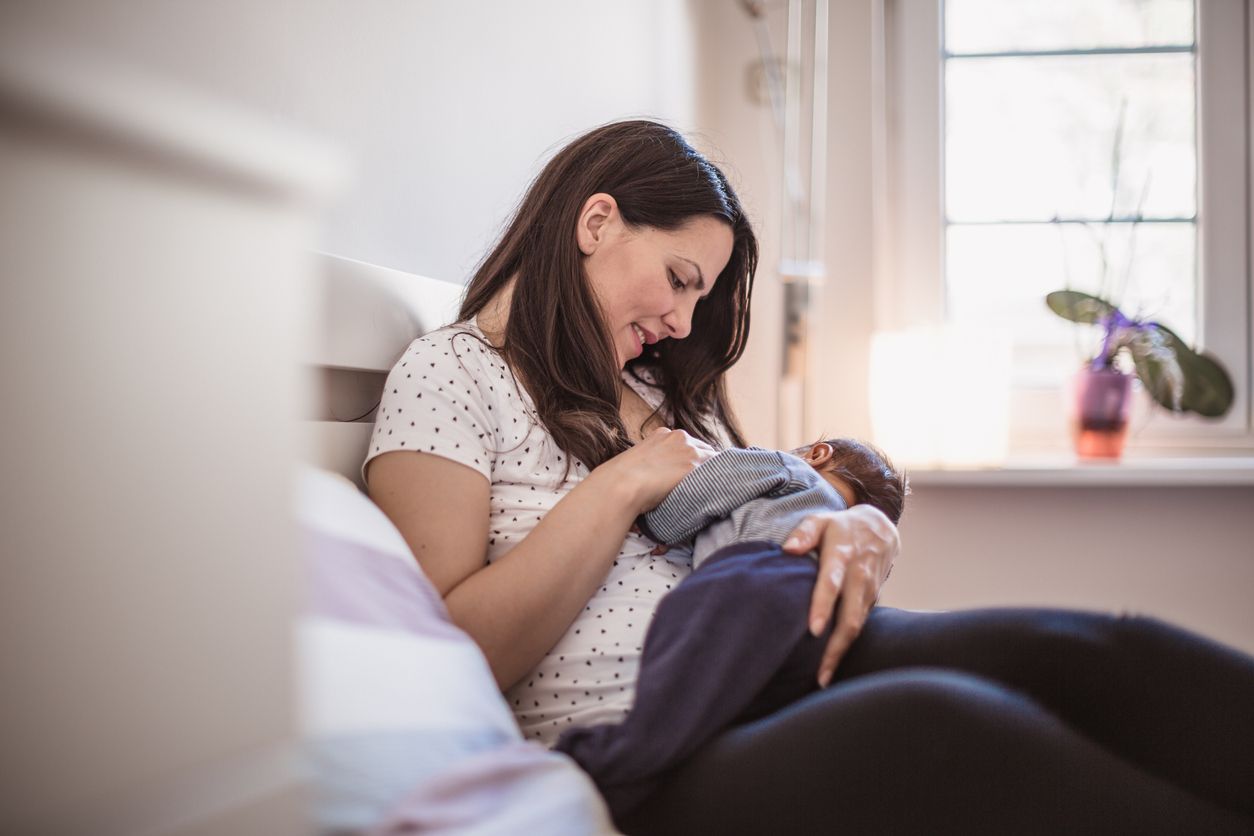 Young mother breastfeeding her baby boy in the bedroom. Belgrade, Serbia