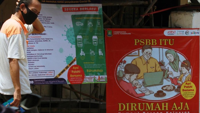Ilustrasi PSBB Warga melintas di depan spanduk sosialisasi akan pentingnya menerapkan Pembatasan Sosial Bersekala Besar (PSBB) yang ada di kawasan Karawaci, Tangerang, Banten, Rabu (22/4/2020). Kota Tangerang merupakan daerah yang menerapkan PSBB yang bertujuan untuk membatasi aktivitas masyarakat yang tidak penting agar dapat memutus matarantai penyebaran COVID-19.