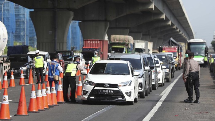 Indonesian police check a car passenger at a checkpoint during the imposition of large-scale restriction to curb the spread of the new coronavirus outbreak on a toll road in Cikarang, West Java, Indonesia, Friday, April 24, 2020. Indonesia is suspending passenger flights and rail service as it restricts people in the worlds most populous Muslim nation from traveling to their hometowns during the Islamic holy month of Ramadan because of the coronavirus outbreak. (AP Photo/Achmad Ibrahim)