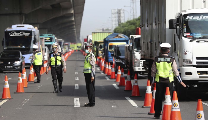 Virus Outbreak Indonesia Indonesian police check a car passenger at a checkpoint during the imposition of large-scale restriction to curb the spread of the new coronavirus outbreak on a toll road in Cikarang, West Java, Indonesia, Friday, April 24, 2020. Indonesia is suspending passenger flights and rail service as it restricts people in the world's most populous Muslim nation from traveling to their hometowns during the Islamic holy month of Ramadan because of the coronavirus outbreak. (AP Photo/Achmad Ibrahim)