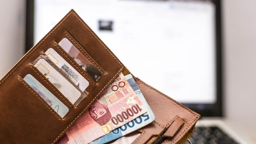 wallet with rupiah money inside in front of computer laptop monitor screen, online transaction concept