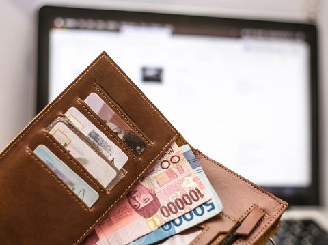 wallet with rupiah money inside in front of computer laptop monitor screen, online transaction concept