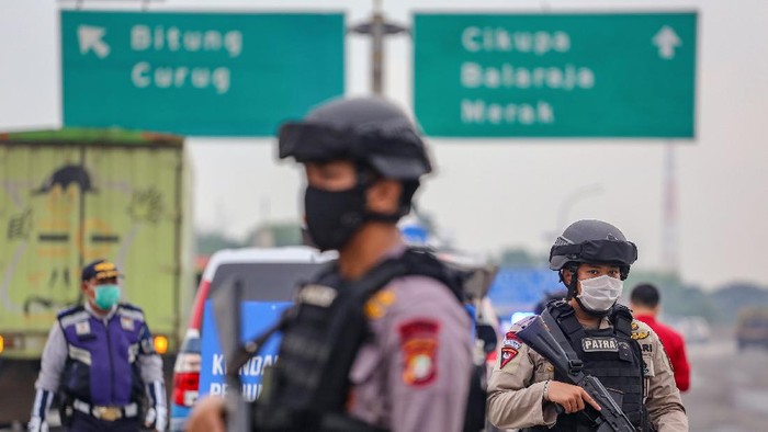 Petugas kepolisian berjaga saat dilakukan penyekatan kendaraan di pintu keluar Tol Bitung, Kabupaten Tangerang, Banten, Jumat (24/4/2020). Penyekatan itu dilakukan menyusul adanya larangan mudik bagi seluruh kalangan yang sudah ditetapkan mulai hari ini guna mencegah penyebaran COVID-19. ANTARA FOTO/Fauzan/wsj.