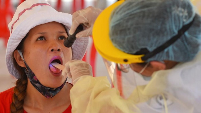 A medical official (R) wears a protective suit, amid concerns over the spread of the COVID-19 coronavirus, as she conducts a physical examination on a migrant worker at a school in Phnom Penh on April 20, 2020. - Health authorities conducted check-ups on workers who returned from their provinces to work in Phnom Penh after the Khmer New Year celebrations, amid concerns over the spread of the COVID-19 novel coronavirus. (Photo by TANG CHHIN Sothy / AFP)