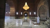 Seorang muazin mengumandangkan azan dari dalam Masjid Jama yang tampak sunyi dari aktivitas para jemaah di bulan suci Ramadhan.