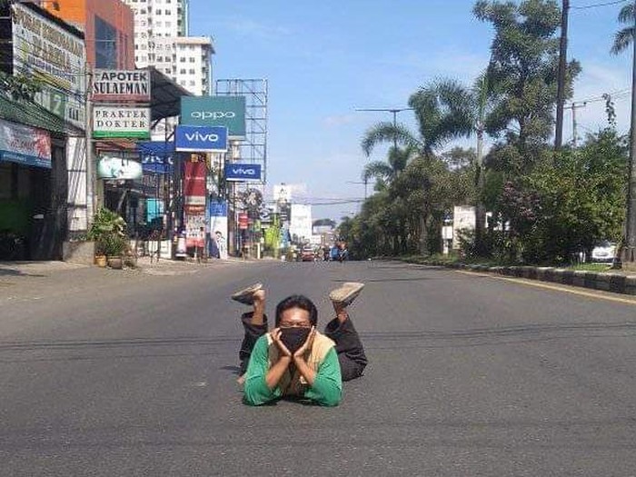 Warga berpose santai di tengah jalan yang sepi