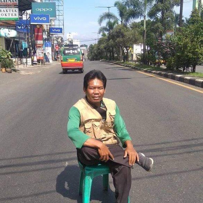 Warga berpose santai di tengah jalan yang sepi