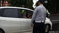 Petugas mengimbau warga untuk menerapkan physical distancing saat berkendara roda empat.
