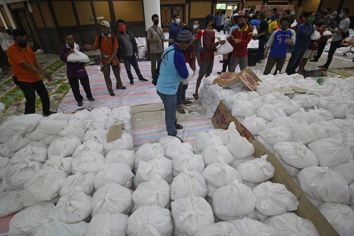 Relawan membungkus paket sembako bantuan dari berbagai perusahaan di Convention Hall, Surabaya, Jawa Timur, Minggu (26/4/2020). Bantuan sembako sebanyak 68.000 paket tersebut akan didistribusikan oleh Pemerintah Kota Surabaya kepada masyarakat berpenghasilan rendah (MBR) di 31 kecamatan yang terdampak COVID-19. ANTARA FOTO/Moch Asim/aww.