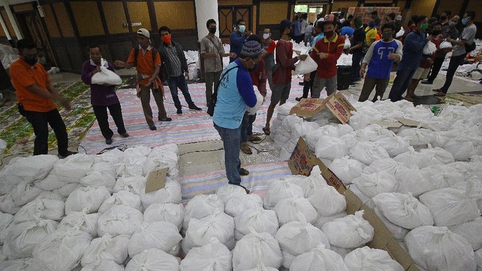 Relawan membungkus paket sembako bantuan dari berbagai perusahaan di Convention Hall, Surabaya, Jawa Timur, Minggu (26/4/2020). Bantuan sembako sebanyak 68.000 paket tersebut akan didistribusikan oleh Pemerintah Kota Surabaya kepada masyarakat berpenghasilan rendah (MBR) di 31 kecamatan yang terdampak COVID-19. ANTARA FOTO/Moch Asim/aww.