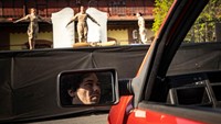 Orang-orang menonton pertunjukan dari mobil mereka di teater drive-in.