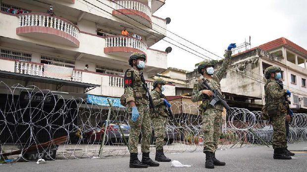 Malaysian army personnel stand guard next to barbed wire in the locked down area of Selayang Baru, outskirt of Kuala Lumpur, Malaysia, on Sunday, April 26, 2020. The lockdown was implemented to allow authorities to carry out COVID-19 screenings to curb the spread of coronavirus. (AP Photo/Vincent Thian)