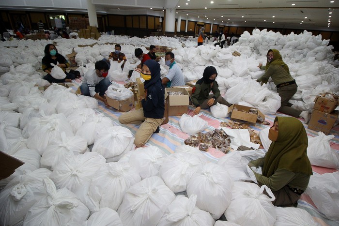 Relawan membungkus paket sembako bantuan dari berbagai perusahaan di Convention Hall, Surabaya, Jawa Timur, Minggu (26/4/2020). Bantuan sembako sebanyak 68.000 paket tersebut akan didistribusikan oleh Pemerintah Kota Surabaya kepada masyarakat berpenghasilan rendah (MBR) di 31 kecamatan yang terdampak COVID-19. ANTARA FOTO/Moch Asim/aww.